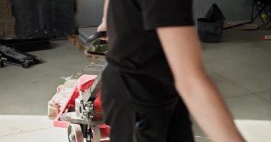 Bir atölyede çalışan erkek teknisyenler profesyonel ekipmanlı bir elektrikli araba pili modülünü inceliyor ve idare ediyor. Otomobil Servisi, Elektrikli Araba Aküsü Taşıma