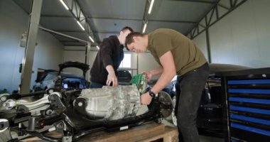 EV onarım konsepti. Otomobil Servisi, Elektrikli Araç Motoru Modern bir otomobil tamirhanesinde parçalanmış bir elektrikli araba motoru üzerinde çalışan iki tamirci, EV bakım ve hizmet sunuyor.