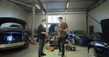 Otomobil servisi, elektrikli araç bakım iki araba tamircisi modern bir otomobil benzin istasyonunda elektrikli araba motoru üzerinde çalışıyor. EV bakım ve onarım kavramı. EV tamir kavramı.