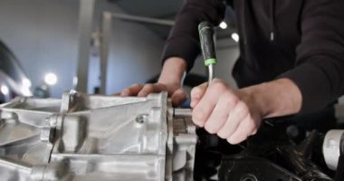 Profesyonel bir oto tamir atölyesinde parçalanmış bir elektrikli araba motorunu tamir eden tamirciye yakın çekim. EV onarım konsepti. Otomobil servisi, elektrikli araç motor bakımı