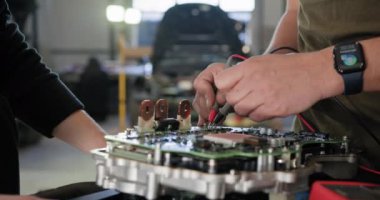 Otomobil tamircisi modern bir atölyede elektrikli araba motorunu denetliyor ve onarıyor. EV bakım ve servis devam ediyor. EV onarım konsepti. Otomobil servisi, elektrikli araç motor bakımı