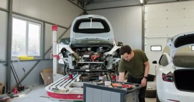 Oto Tamirhanesi 'nde Tamirci Araba. Modern, iyi donanımlı bir oto tamirhanesinde araba tamiri yapan bir tamirci. Resim, bir aracın gövdesini ve bileşenlerini düzeltmenin karmaşık sürecini gösteriyor.