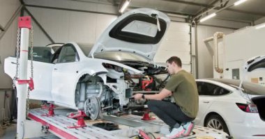 Modern, iyi donanımlı bir oto tamirhanesinde araba tamiri yapan bir tamirci. Resim, bir aracın gövdesini ve bileşenlerini düzeltmenin karmaşık sürecini gösteriyor.