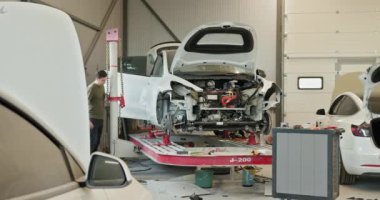 Tamircinin çalıştığı modern araba tamir atölyesi. Araba tamiri ve modern bir atölyede vücut hizalaması üzerinde çalışan bir tamirci. Araç onarımının çeşitli aşamaları görünür.