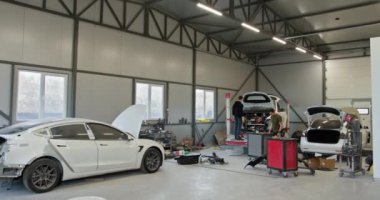 Bir kazadan sonra tamircilerin araba tamir ettiği temiz, modern bir oto tamir atölyesi. Tamir ve bakım yapılan geniş garaj araçları. Arabalı Modern Otomobil Tamir Atölyesi