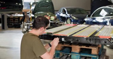 Modern bir atölyede elektrikli araba aküsü modülünü tamir eden teknisyen. Yüksek voltajlı lityum iyonlu batarya üretim hattında. Elektrikli araba. Batarya hücre modülü sürüsü. EV arabası