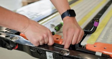 Bir servis merkezinde elektrikli bir araç için lityum iyon bataryası üzerinde çalışan bir teknisyenin elleri. Elektrikli araba. Batarya hücre modülü sürüsü. EV arabası. Elektrikli Araç Pili Tamiri