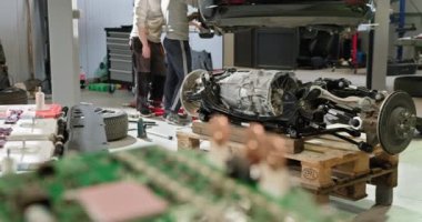 Modern bir tamir atölyesinde elektrikli araba aküsü üzerinde çalışan teknisyenler. Çeşitli bileşenler ve araçlar görünür, teknik onarım çalışmaları vurgulanır. Batarya hücre modülü sürüsü. EV arabası