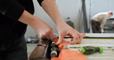 Modern bir atölyede elektrikli araba aküsünün tamiri için çalışan teknisyenlerin yakın çekimi. Atölyedeki elektrikli araba aküsünü tamir eden teknisyen. Elektrikli araba..