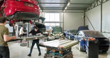 Modern bir otomotiv atölyesinde elektrikli araba akülerini tamir etmeye ve monte etmeye çalışan bir grup tamirci. Tamirci atölyedeki elektrikli araba akülerini tamir ediyor. Elektrikli araba. Pil paketi