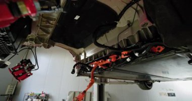 Modern bir atölyede kısmen parçalanmış bir elektrikli araç motorunu denetleyen tamirci. EV bakım, servis ve onarım kavramı. EV onarım konsepti. Servis, Elektrikli Araba Aküsü İşleme.