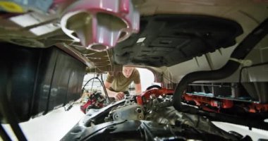 Tamirci parçalanmış elektrikli araba motorunu inceliyor ve onarıyor. Modern elektrikli araç bakım ve servisi. EV onarım konsepti. Otomobil Servisi, Elektrikli Araba Aküsü Taşıma.
