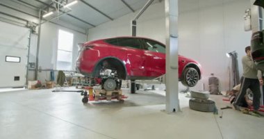 Makinist parçalanmış bir elektrikli araba motorunda bakım yapıyor. Modern elektrikli araç tamiri ve servis konsepti. EV onarım konsepti. Otomobil Servisi, Elektrikli Araba Aküsü Taşıma.