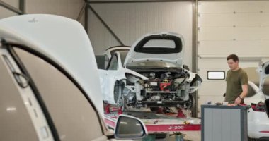 Araba tamiri ve modern bir atölyede vücut hizalaması üzerinde çalışan bir tamirci. Araç onarımının çeşitli aşamaları görülebilir. Tamirciyle Çağdaş Araba Tamir Atölyesi