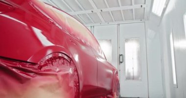 Özel bir boya odasında resim yapan bir otomobil. Araba profesyonel bir oto tamirhanesinde yeni bir kat kırmızı boya ile kaplanıyor. Otomotiv Boyama Odasında Boyanan Araba