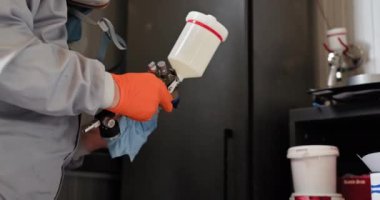 Otomotiv teknisyeni araba tamiri için boya hazırlıyor. Korumalı ekipmanlı otomotiv teknisyeni bir benzin istasyonunda araba tamirine boya hazırlıyor. Sprey tabancaya ve boya kutusuna odaklan.