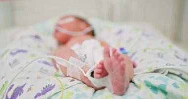 Yenidoğan bebekler, yeni doğan yoğun bakım ünitesinde tıbbi ekipmanlarla. Bebek ayaklarına ve hastane çevresine odaklan. Bebek sağlıklı gelişim için gerekli bakım ve izleme.