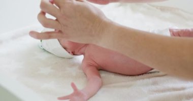 Eller nazikçe yeni doğan ellere masaj yapıyor rahatlatıcı ve rahatlatıcı bir atmosfer yaratıyor. Bebek yumuşak masasında temalı bere ve bebek bezi giyiyor. Sıcak ellerle ve yumuşak dokunuşla yumuşak bebek masajı.