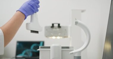 Bilim adamı modern araştırma tesisinde laboratuvar ekipmanı kullanıyor. Eldivenli el hazırlama cihazı araştırma için. Bilgisayarın arka planda DNA dizilimini gösteren yüksek teknoloji laboratuvar ayarları.
