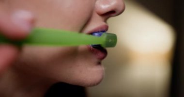 Parlak yeşil bir diş fırçasıyla dişlerini fırçalayan birinin yakın çekimi, ağız bakımının önemini vurguluyor. Günlük Ağız Temizliği Rutini Dişlerinizi Derinden Fırçalamanın Kapanışı