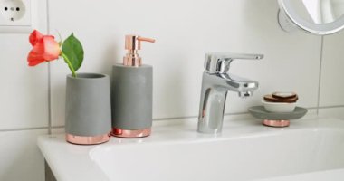 Şık gri ve gül sarısı banyo aksesuarları, güzel bir çiçek aksanı ve gösterişli modern bir musluğu var. Ev Dekorunuz İçin Modern Tasarımlı Zarif Banyo Aksesuarlarını Keşfedin