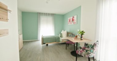 Bu şık yaşam alanı açık renkler, canlı çiçek aksanları ve bol miktarda doğal ışık sergiliyor. Çiçek aksanlı ve yeşil duvarlı modern minimalist yatak odası