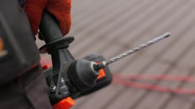 İnşaat alanında tanınmayan bir inşaat işçisi elinde bir iş aleti, matkap ya da elektrikli aletler tutuyor. Konsept: inşaat ve onarım. Bir inşaat şirketi için ekran koruyucu.