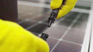 Elektrik kablosunu güneş panellerine bağla. Güneş panellerinin bağlanması ve kurulumu. Güneş enerjisi ağıyla bağlantı. Eldivenli bir elektrikçi kabloyu bağlıyor..