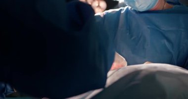 Maskeli cerrahlar hastanede modern ameliyat yapıyorlar. Hassasiyete, takım çalışmasına, steril ortama odaklan. Asyalı ve beyaz profesyoneller ışıklar altında cerrahi müdahalede bulundular.