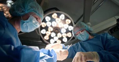 Modern ameliyathanede ameliyat yapan iki kadın cerrah. Parlak cerrahi ışıkları var. Takım çalışmasına, hassasiyete ve tıbbi uzmanlığa odaklan. Karmaşık tıbbi prosedür sırasında cerrah odaklandı