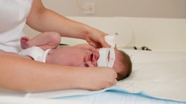 Klinikte fototerapi gören yeni doğmuş bir bebek. Doktorların da yardımıyla. Bebeğin ultraviyole ışık prosedürü sırasında göz koruması var..