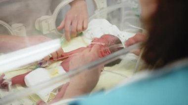 Yenidoğan yoğun bakım ünitesinde prematüre bir bebeğe bakılıyor, tıbbi personel de katılıyor. Prematüre bir bebek, yenidoğan yoğun bakım ünitesinde bakım görür.