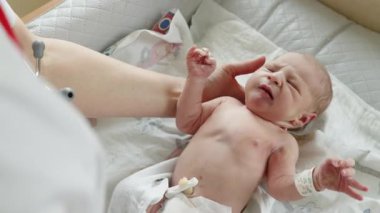 Yeni doğmuş bir bebek beyaz bir kıyafet giyer ve hayatının ilk günlerini gözler önüne serer..