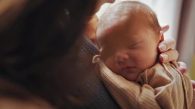 Yeni doğmuş bir bebek, ebeveynlerinin kollarında huzur içinde uyur. Şefkat, sevgi ve aile duyguları uyandırır..