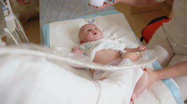 Tıbbi bir ortamda ultrason muayenesinden geçen bir bebek. Çocuk tıbbi bir masada yatıyor. Sağlık ekibi ultrason testini yapıyor. Bir Bebek İçin Ultrason Sınavı