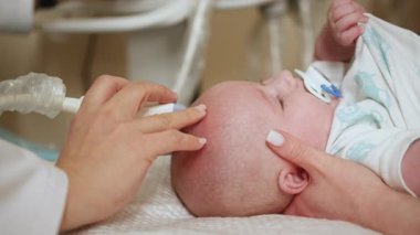 Kafasına ultrason uygulanan bir bebek. Görüntü, genç çocuklarda erken teşhis için ultrason kullanımını vurguluyor.