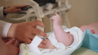 Bir bebeğe ultrason çekiliyor ve çocuğun eli tıbbi cihaza dokunuyor. Bebek için ultrason muayenesi. Çocuk sağlık masasında yatıyor..