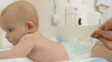 Bebek, steteskoplu bir doktor tarafından muayene edilir ve sağlığı ve sağlığı üzerinde yoğunlaşır. Çocuk sağlık kontrolü sırasında bir masanın üzerinde yatıyor. Doktor Bebeği İnceleme