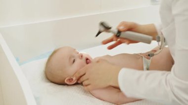 Bir doktor, klinikte ya da hastane ortamında bir bebeği nazikçe muayene eder. Doktor Bebeği İnceleme