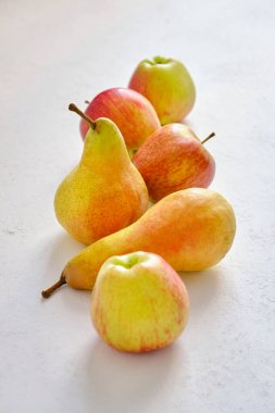 Taze ve sulu kırmızı elmalar ve sarı armutlar yakın plan beyaz bir masada.