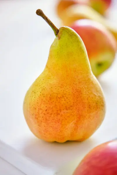 Taze ve sulu kırmızı elmalar ve sarı armutlar yakın plan beyaz bir masada.