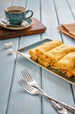 Süzme peynirli taze gözleme ve mavi ahşap bir masada sade kahve.