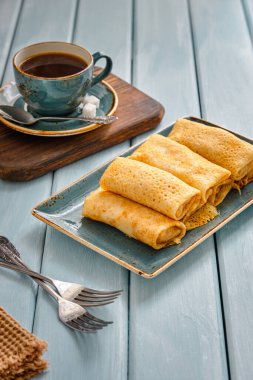 Süzme peynirli taze gözleme ve mavi ahşap bir masada sade kahve.