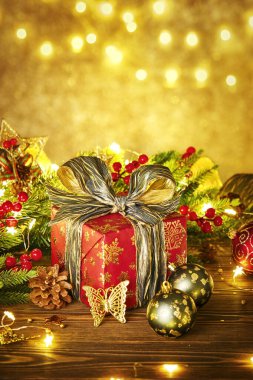 Lambalardan bir çelenk ile Noel kompozisyonu. Noel ağacı dalları, kırmızı hediye kutusu toplar, külahlar ve ahşap bir masanın üzerindeki altın dekor.