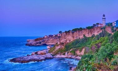 Sile, Türkiye, Deniz feneri Karadeniz 'in kayalık kıyılarında gün batımından sonraki akşam mavi gökyüzüne karşı. Şehrin popüler tarihi yeri.