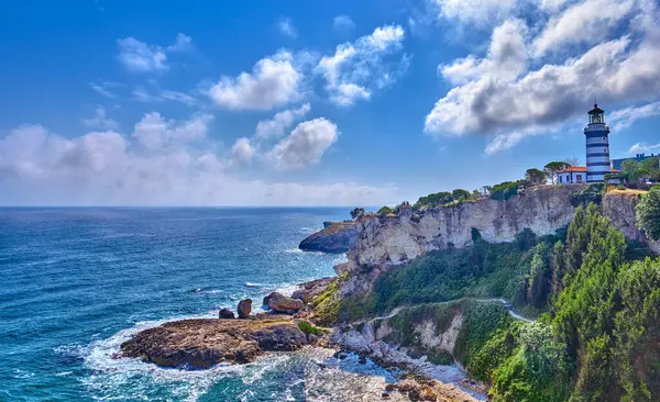 Karadeniz 'in kayalık kıyılarındaki Sile, Türkiye, Deniz feneri bulutlu mavi gökyüzünün arka planına karşı. Şehrin popüler tarihi yeri.