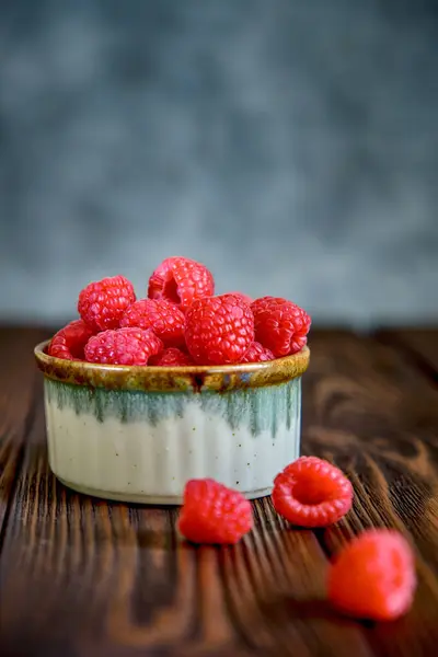 Taze ahududu, bir fincanda, ahşap bir masada yakın plan.