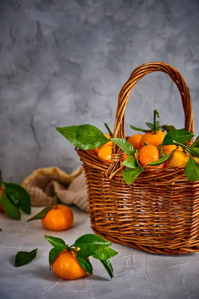 Gri arka planda taze ve sulu mandalinalı sepet.