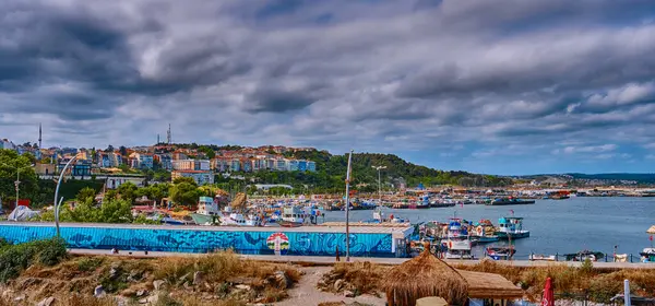 Sile, Türkiye, 8 Temmuz 2025, Karadeniz 'deki şehrin manzarası, rıhtımda duran tekneler, setin üzerinde yürüyen insanlar.
