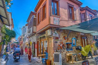 Ayvalik, Türkiye, 13 Temmuz 2025, Renkli evleri, kafeleri ve dükkanları olan kentin merkezindeki sokaklar, insanlar sokaklarda yürüyor